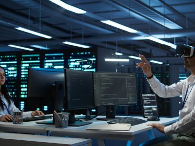 Data center admin responsible for installation of networking systems wearing high tech VR headset. IT worker doing maintenance on server farm gear using virtual reality technology, camera B